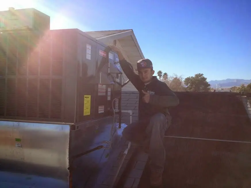 HVAC technician performing AC Tune-Up on a rooftop unit in East Camden